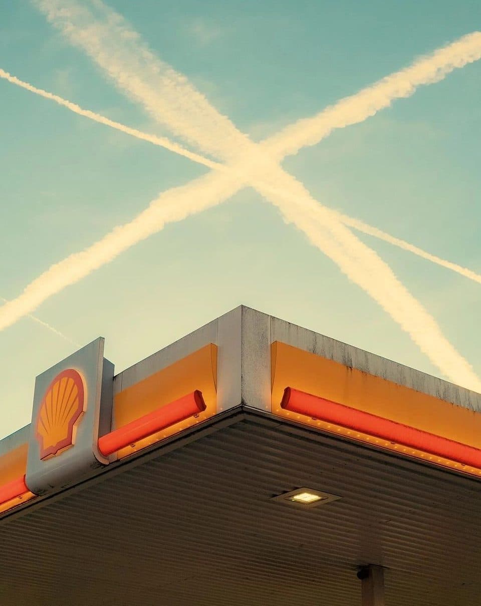 The lit canopy of a fuel station at dusk.